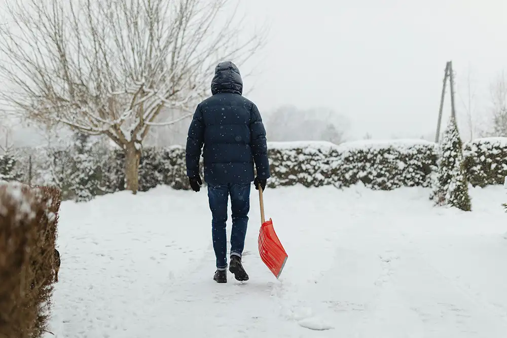 Person som håller i en skyffel i ett snölandskap